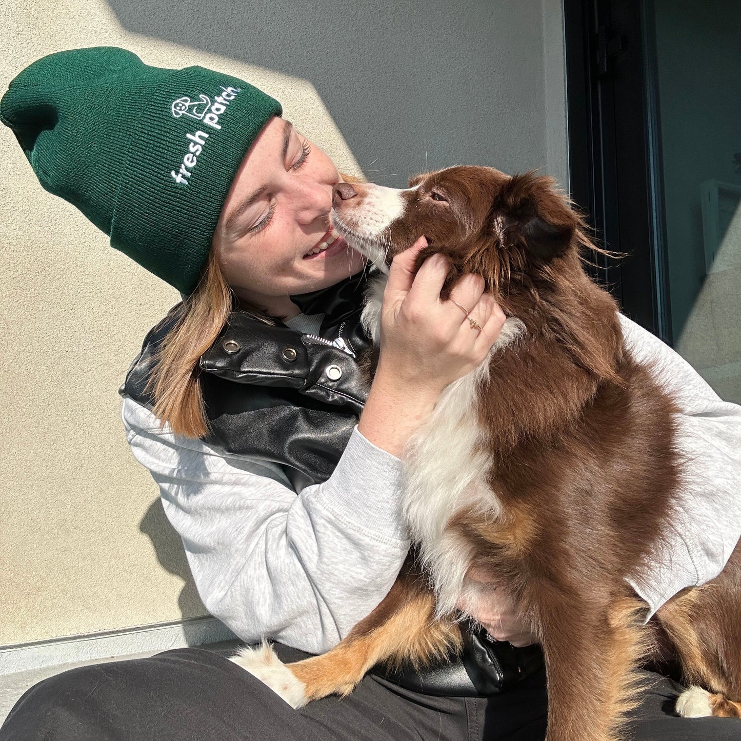 Woman in Green Beanie playing with Red Tri Mini Australian Shepherd