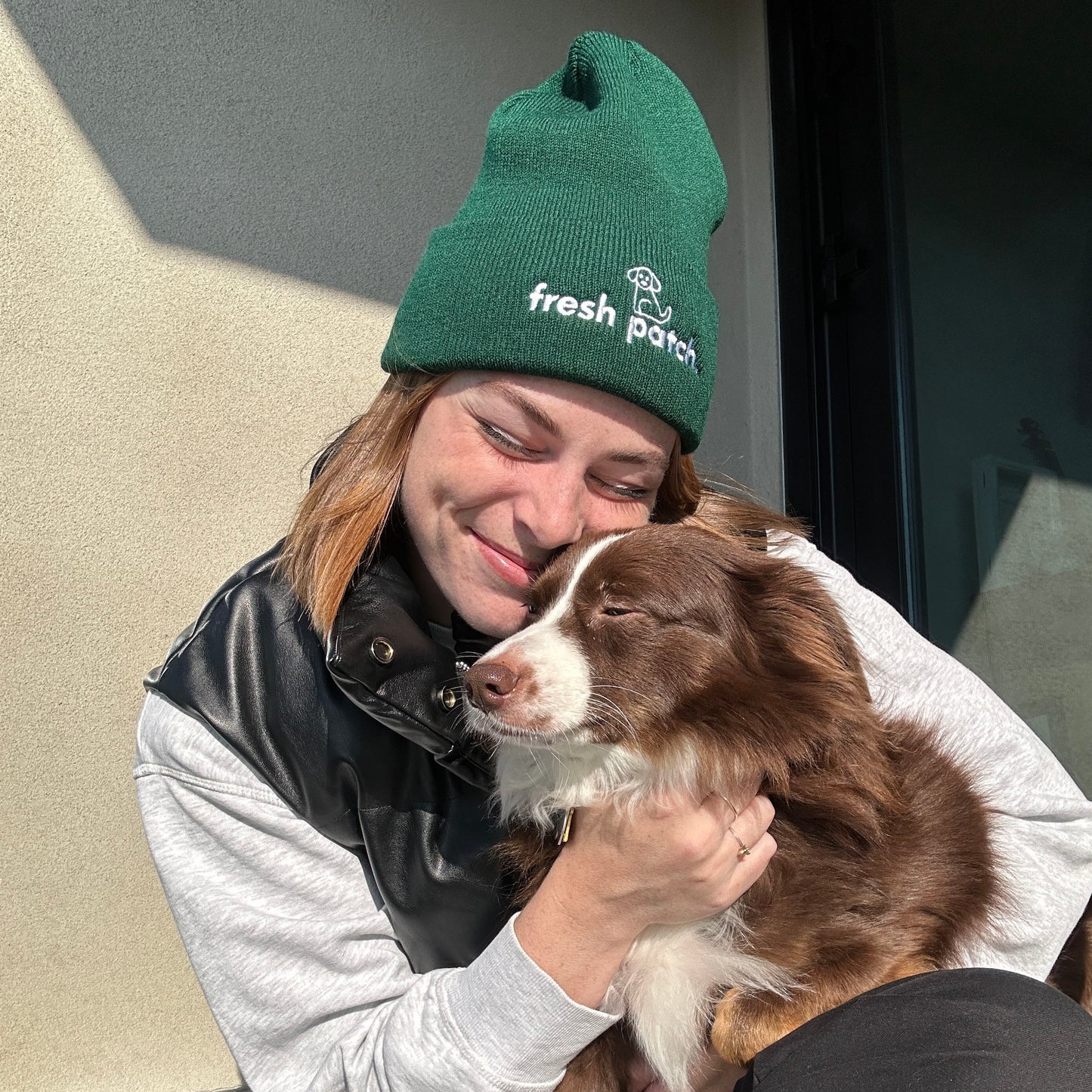 Woman in Green Beanie hugging Red Tri Mini Australian Shepherd